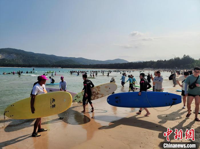 图为“五一”期间的三亚后海，游客抱着冲浪板体验冲浪。　王晓斌 摄