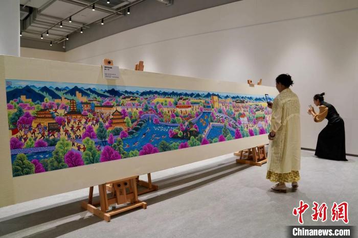 两位画家观赏、拍摄参展作品。　钱晨菲 摄